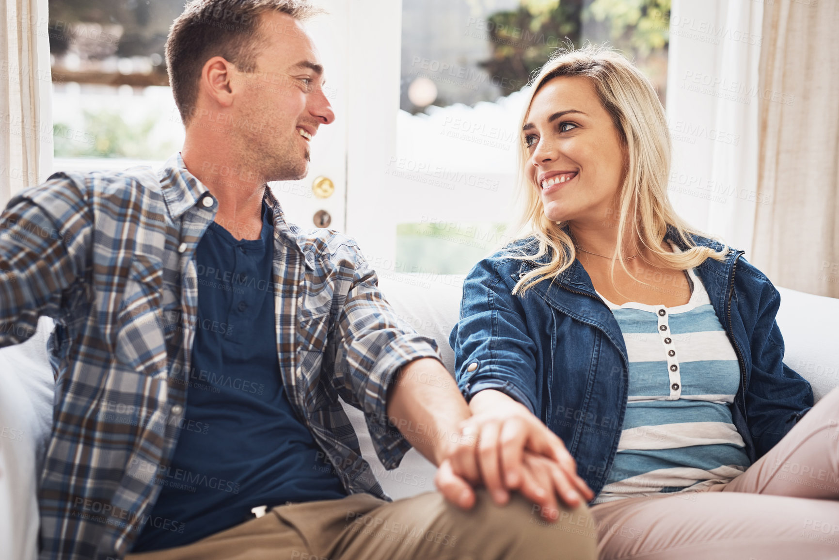 Buy stock photo Holding hands, love and smile with couple on sofa in home living room for bonding, relationship or romance. Happy, relax or wellness with man and woman in apartment for morning or weekend free time