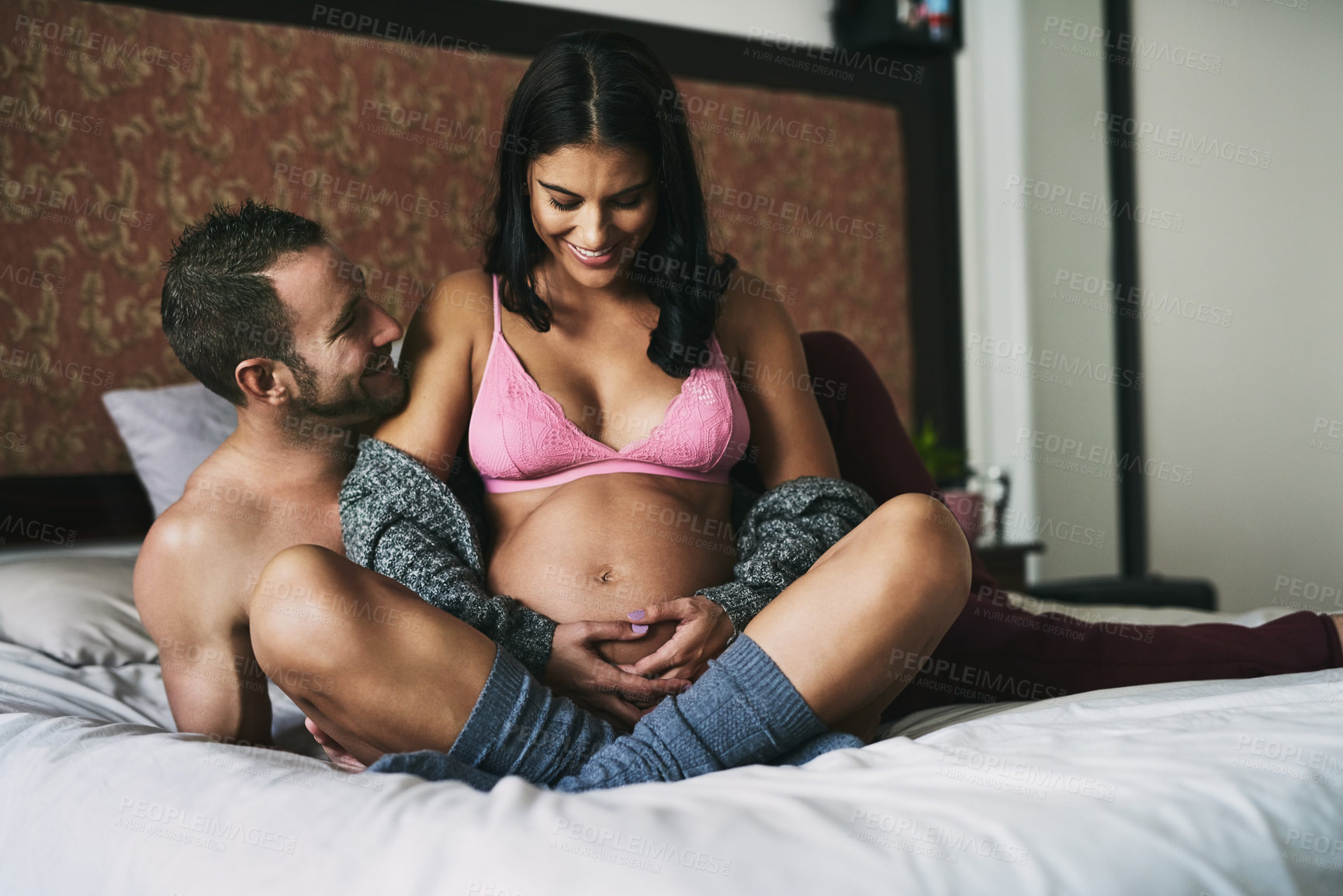 Buy stock photo Full length shot of a handsome young man loving his pregnant wife in their bedroom