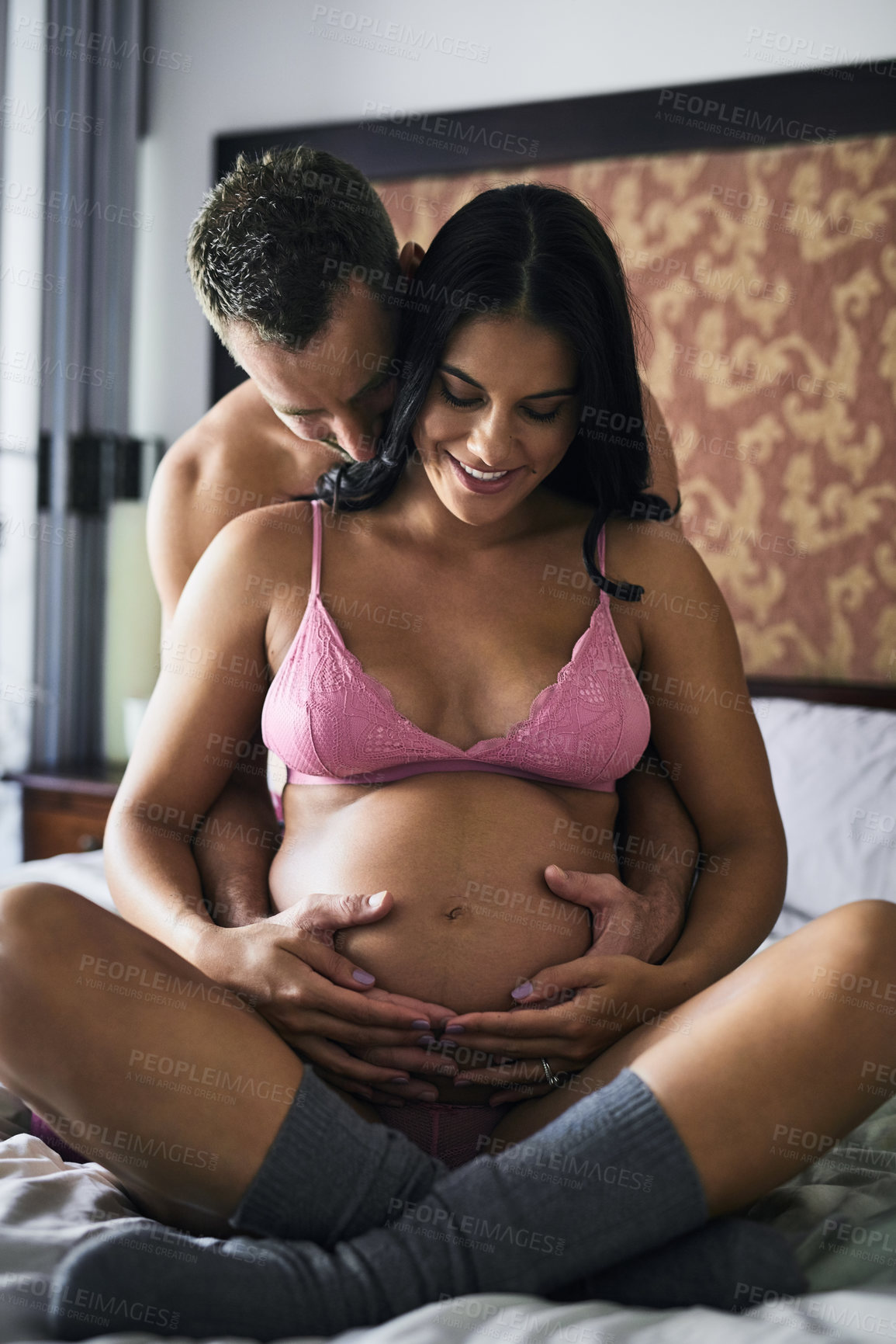 Buy stock photo Couple, home and hug in bed with pregnancy for affection with love, sexual and bonding or trust. People, relationship and smile in lingerie for romance on valentines day, anniversary and sensual