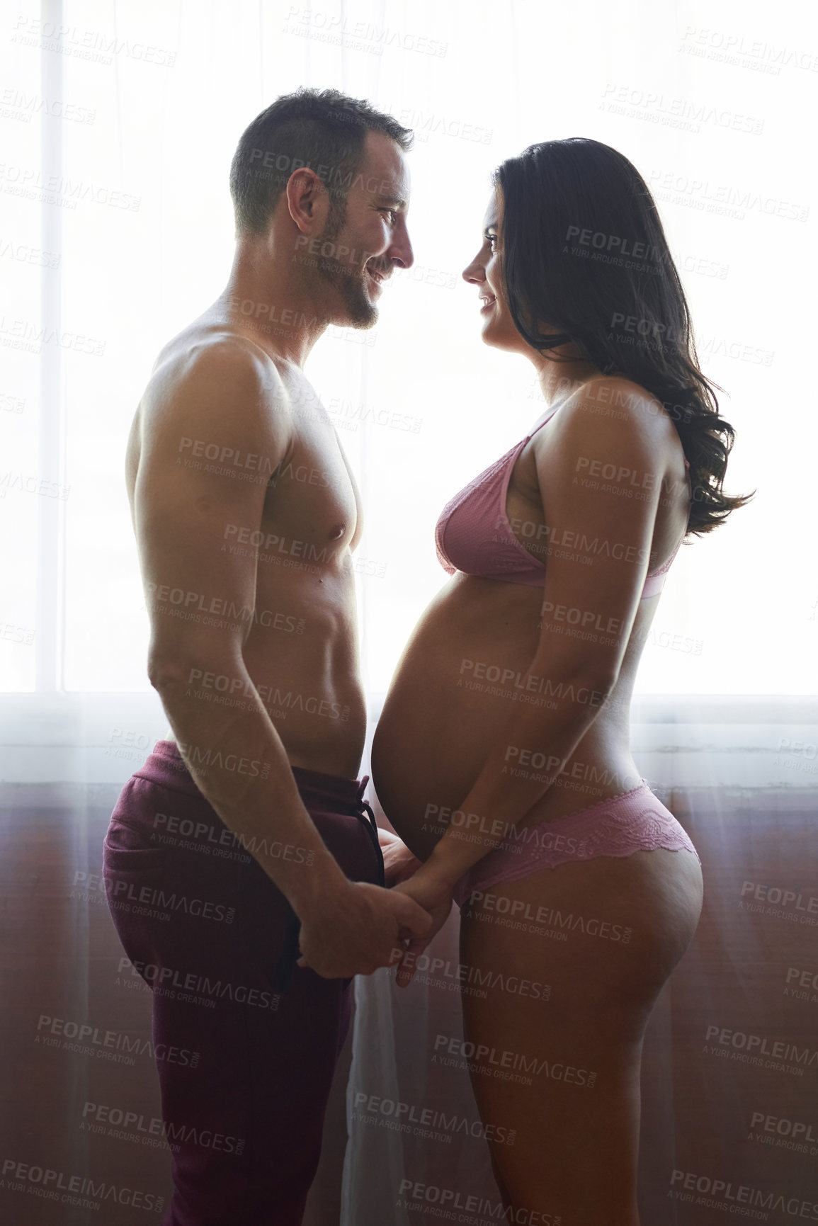 Buy stock photo Pregnancy, happy couple and holding hands in bedroom for love, prenatal care and maternity in home. Man, pregnant woman and support for romance, future family and commitment together in underwear