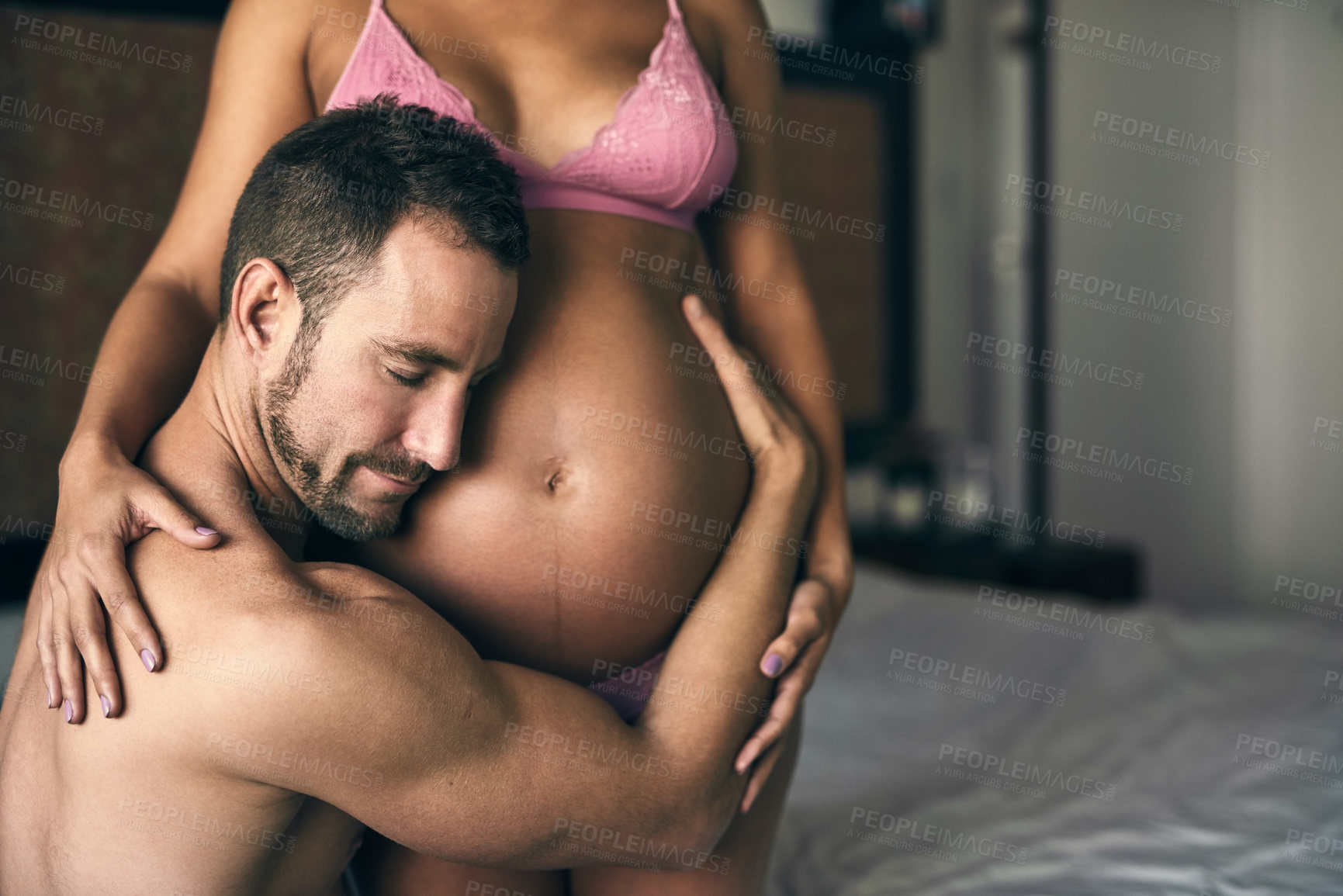 Buy stock photo Pregnant, couple and listening to stomach in bedroom for bonding with baby, love and feeling kick. Maternal support, people and excited for parenting in house with lingerie, heartbeat and embrace mom