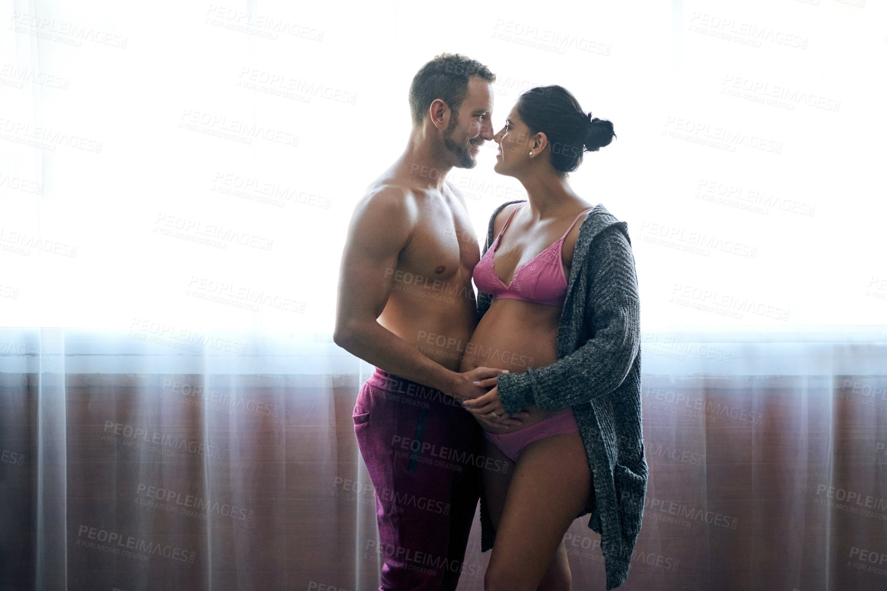 Buy stock photo Cropped shot of a handsome young man loving his pregnant wife in their bedroom