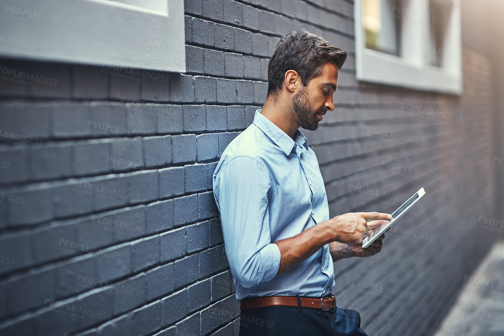 Buy stock photo Business man, tablet and web research, reading email or info online on a wall in urban city. Serious, digital tech and person scroll on app or consultant networking outdoor on social media in street