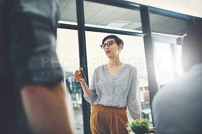Buy stock photo Low angle shot of a young businesswoman addressing her colleagues in the office