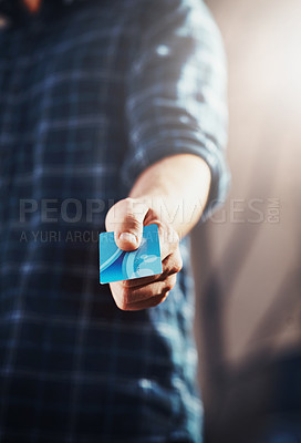 Buy stock photo Male customer holding his credit card in his hand to complete and pay for his shopping purchase. Guy choosing an electronic finance payment method for paying. Retail shop client ready to spend money