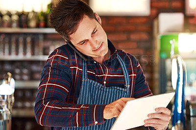 Buy stock photo Shot of a restaurant owner talking on his phone while using a digital tablet