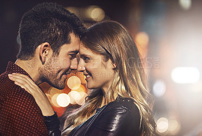 Buy stock photo Shot of a happy young couple standing together outside at night