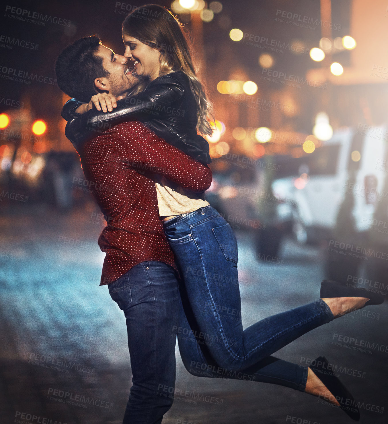 Buy stock photo Shot of a happy young couple standing together outside at night