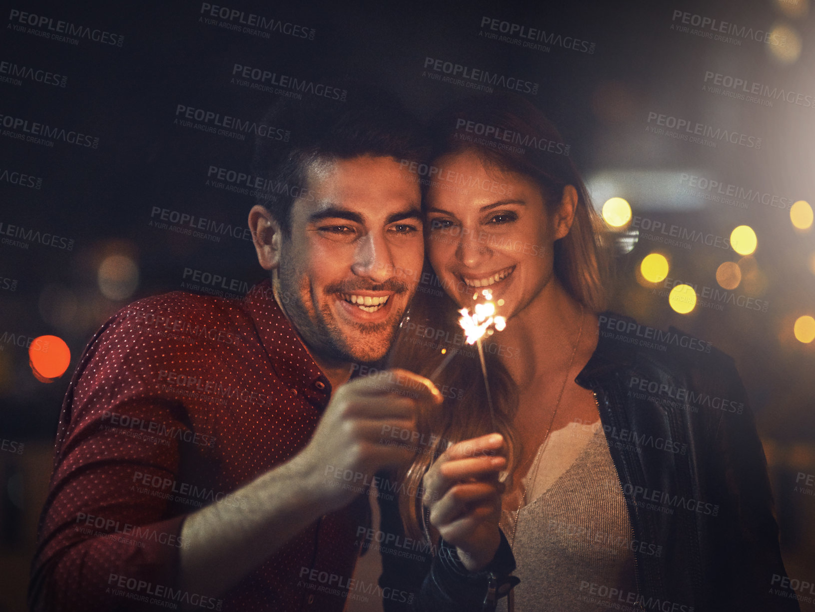 Buy stock photo Smile, couple and sparklers at night for party, celebration and event together outdoor in city with bokeh light. Happy, man and woman with fireworks on holiday, romantic date or laugh on vacation