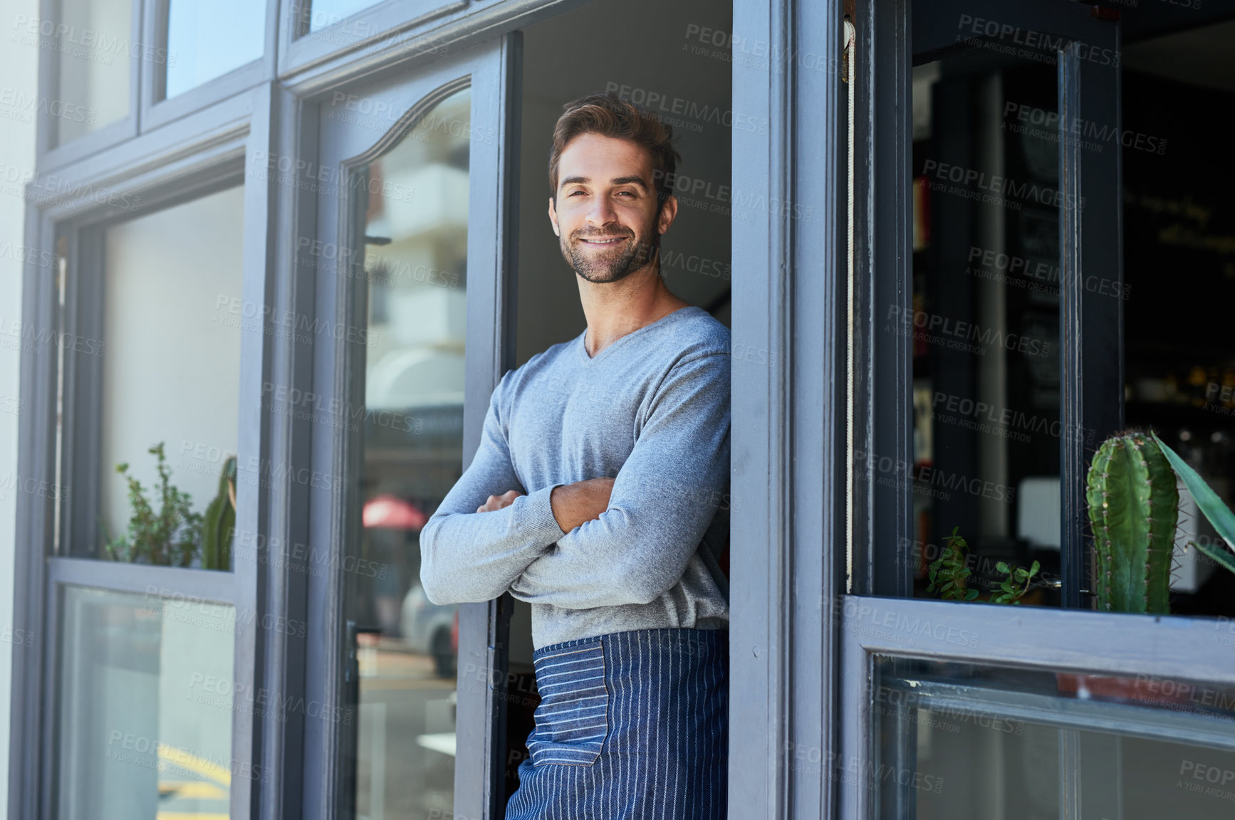 Buy stock photo Door, smile and portrait of barista by coffee shop with positive, happy and confident attitude. Crossed arms, pride and man waiter standing by cafe or restaurant entrance for welcome in hospitality.
