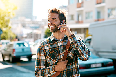 Buy stock photo Shot of a handsome young man using his mobile phone while out in the city
