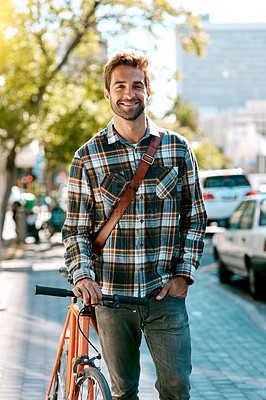 Buy stock photo Shot of a handsome young man walking with a bicycle down a city street