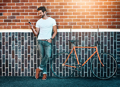 Buy stock photo Man, bicycle or bricks in city with phone for fashion, cycling for environment with sustainability. Male person or wall in urban with mobile and bike, confident or lens flare for communication