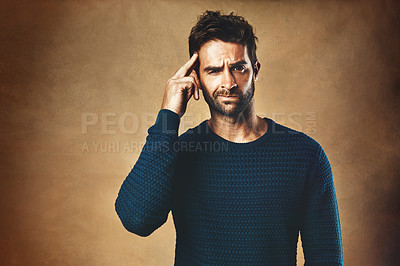 Buy stock photo Studio portrait of a handsome young man scratching his head against a brown background