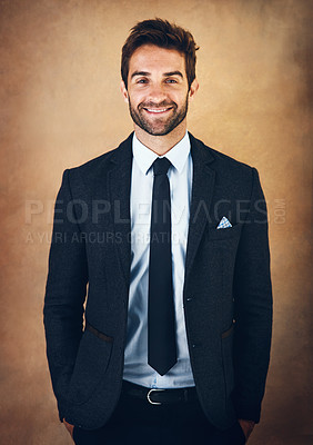 Buy stock photo Studio portrait of a handsome young businessman posing against a brown background
