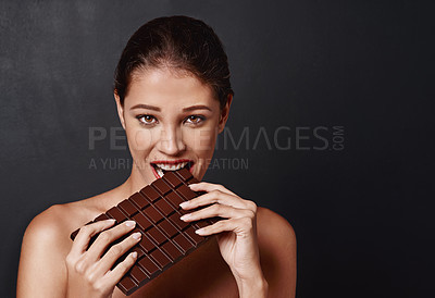 Buy stock photo Chocolate slab, woman and portrait in studio eating for unhealthy diet, craving sugar or cheat day on dark background. Bite, face and female model for snack temptation, sweet addiction or cacao bar