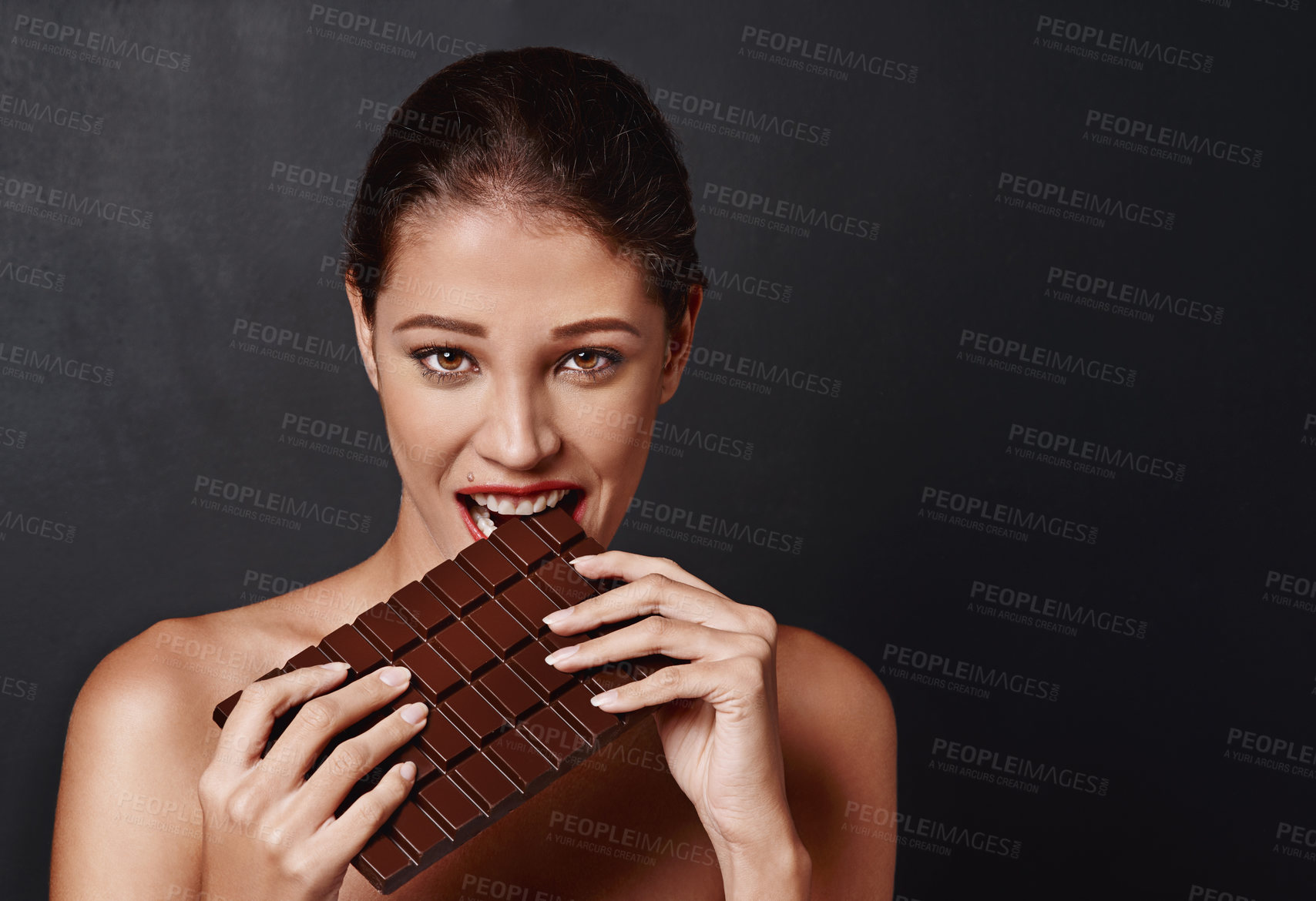 Buy stock photo Chocolate slab, woman and portrait in studio eating for unhealthy diet, craving sugar or cheat day on dark background. Bite, face and female model for snack temptation, sweet addiction or cacao bar