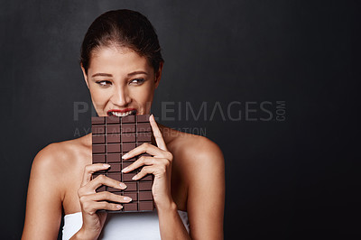 Buy stock photo Chocolate, dessert and woman in studio eating for unhealthy diet, craving sugar or cheat meal on dark background. Bite, calories and female model for snack temptation, sweet addiction or cacao candy