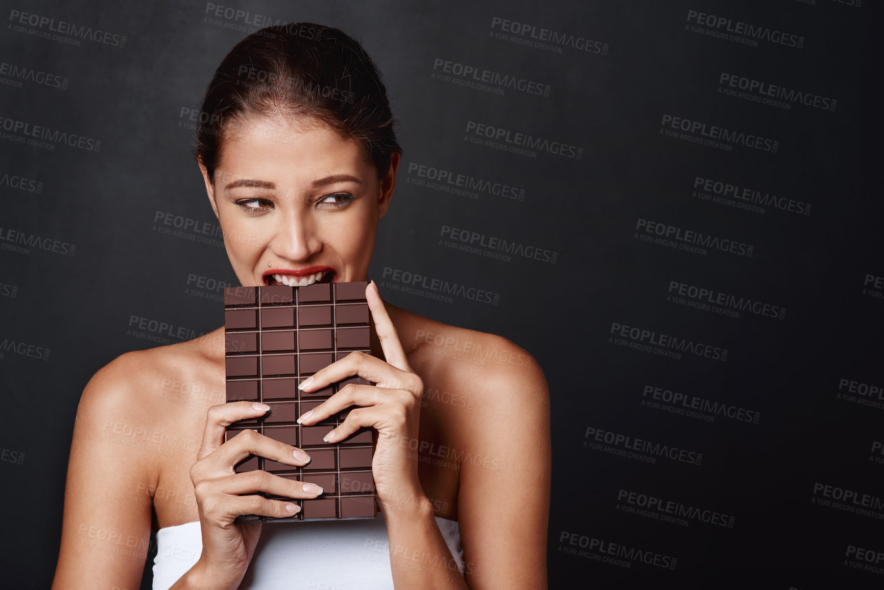 Buy stock photo Chocolate, dessert and woman in studio eating for unhealthy diet, craving sugar or cheat meal on dark background. Bite, calories and female model for snack temptation, sweet addiction or cacao candy