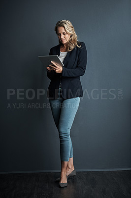 Buy stock photo Studio shot of a mature businesswoman using a digital tablet against a grey background