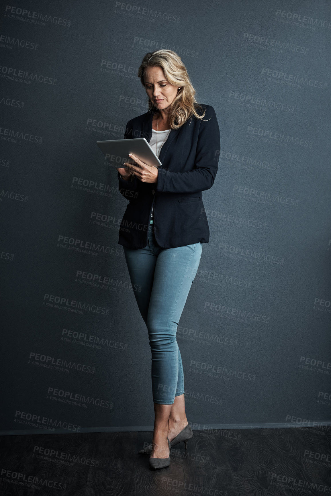 Buy stock photo Studio shot of a mature businesswoman using a digital tablet against a grey background