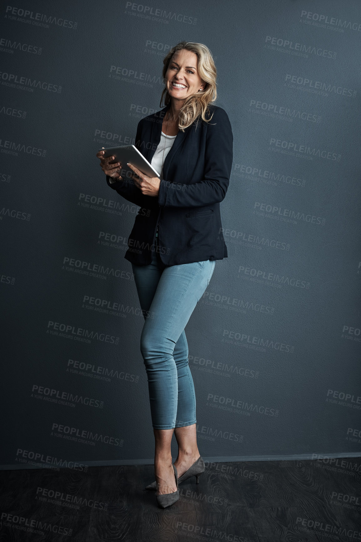 Buy stock photo Studio portrait of a mature businesswoman using a digital tablet against a grey background