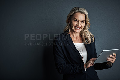 Buy stock photo Studio portrait of a mature businesswoman using a digital tablet against a grey background