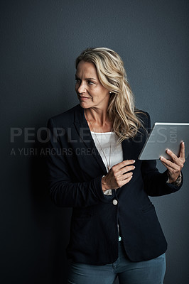 Buy stock photo Studio shot of a mature businesswoman using a digital tablet against a grey background