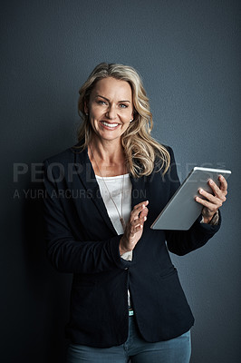 Buy stock photo Studio portrait of a mature businesswoman using a digital tablet against a grey background