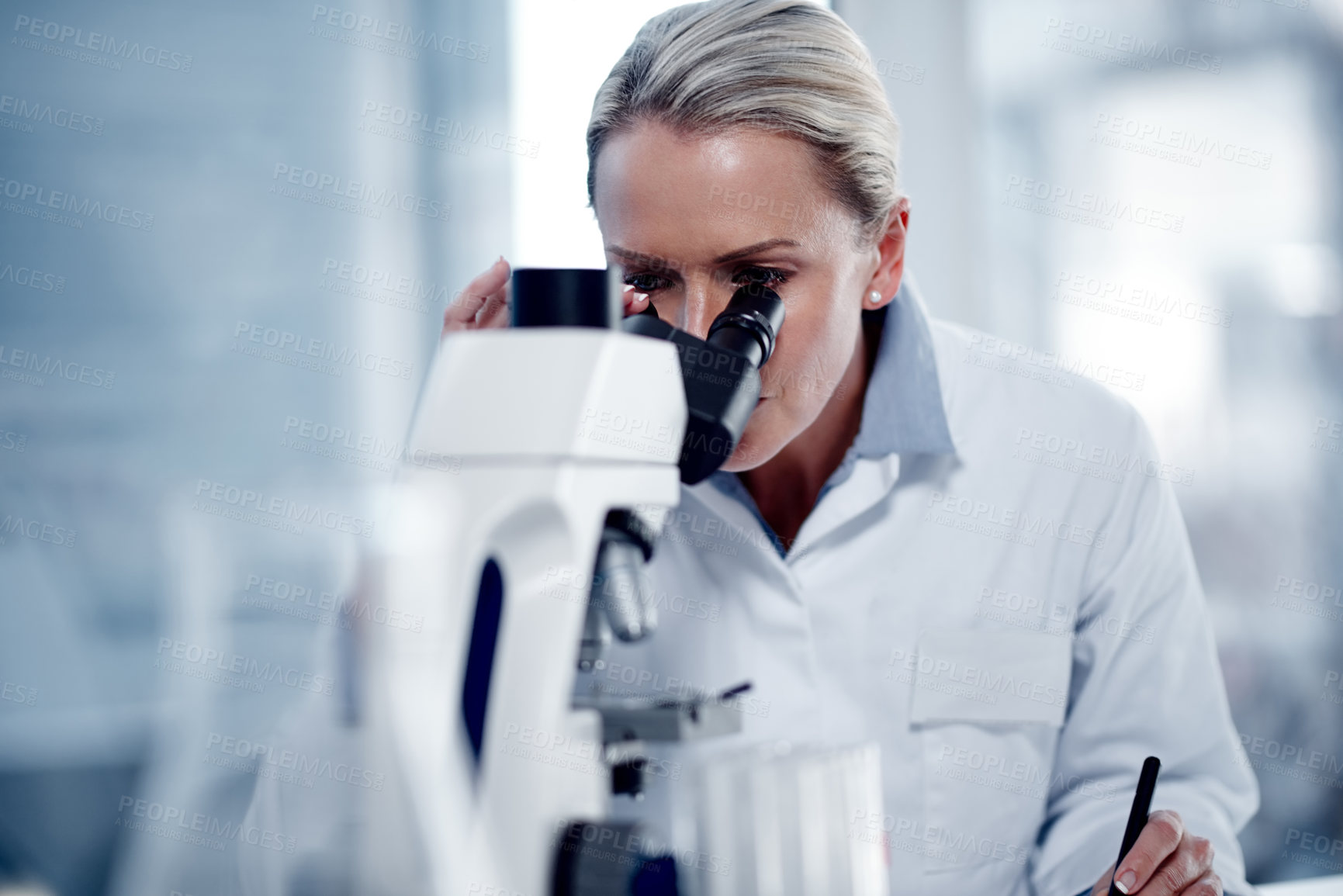 Buy stock photo Shot of a mature scientist using a microscope in her lab