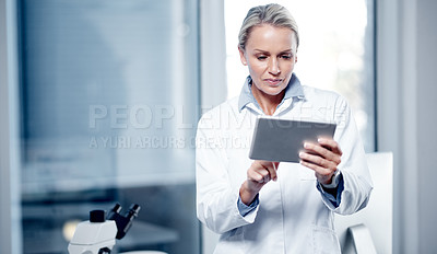 Buy stock photo Shot of a mature scientist using a digital tablet while working in her lab
