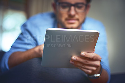 Buy stock photo Shot of a young man using a digital tablet on the sofa at home