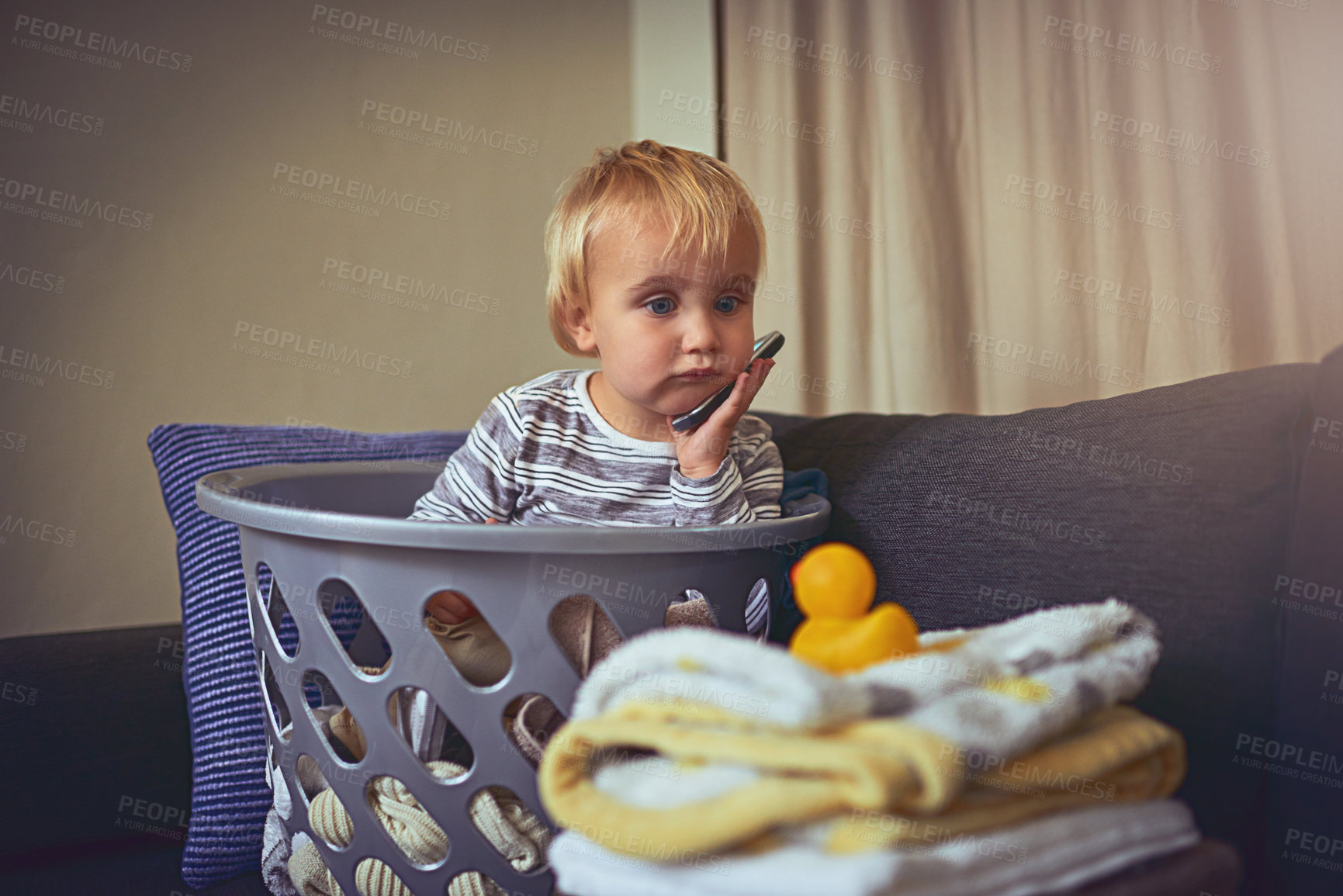 Buy stock photo Shot of an adorable little boy sitting in a basket full of clean laundry