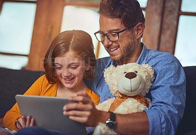 Buy stock photo Shot of a father and daughter using a digital tablet together on the sofa at home