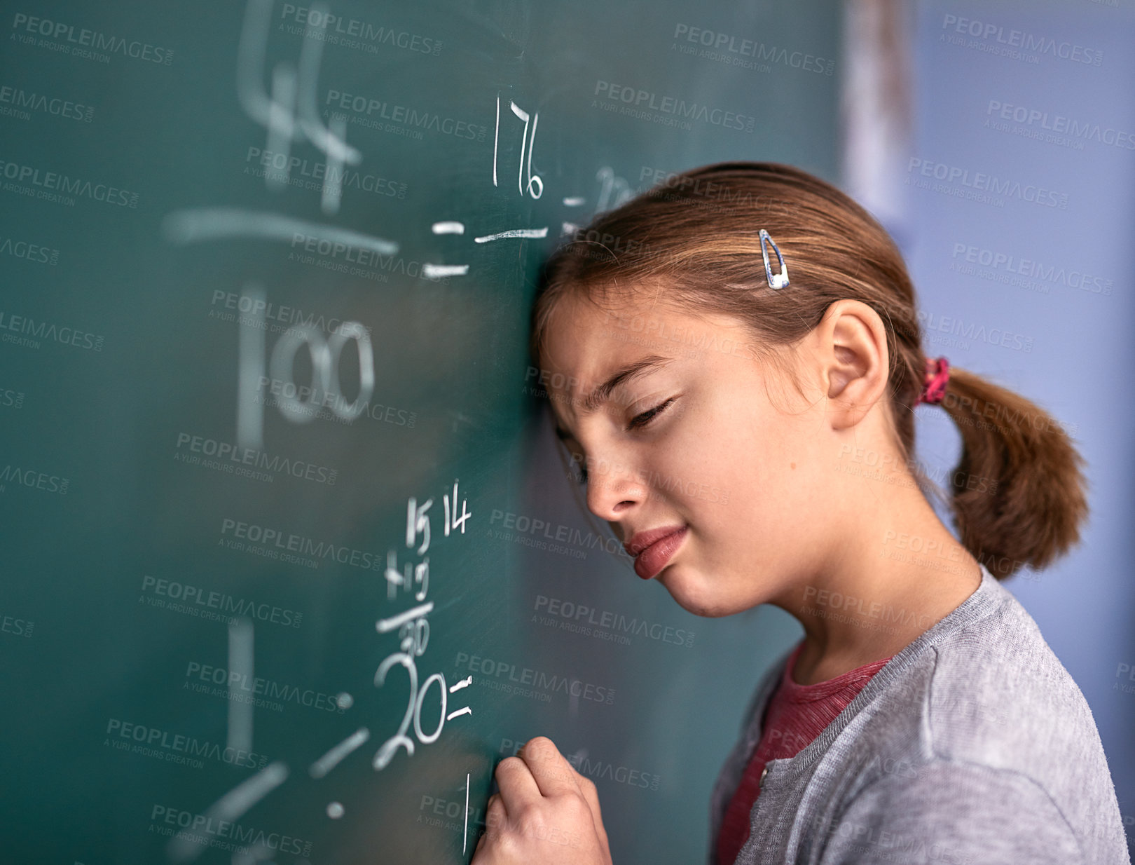 Buy stock photo Cropped shot of an elementary school girl pressing her head against the blackboard with frustration in class