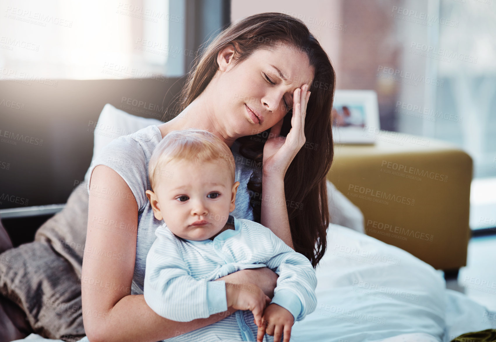 Buy stock photo Stress, headache and a a mother with her baby in a bedroom of their home together in the morning. Children, family and burnout with a tired mama sitting on a bed with an infant son as a single parent