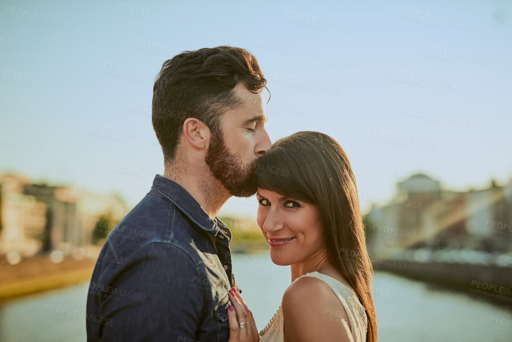 Buy stock photo Cropped shot of a handsome young man kissing his girlfriend on the forehead while on a date