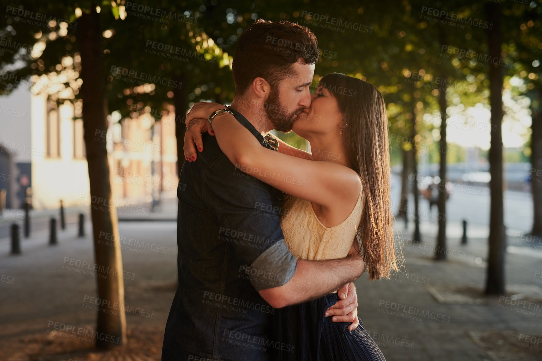 Buy stock photo Kissing, love and couple with hug in nature for romance, connection and happiness together. Care, embracing and young people with bonding for sweet moment, commitment or marriage outdoor in city.