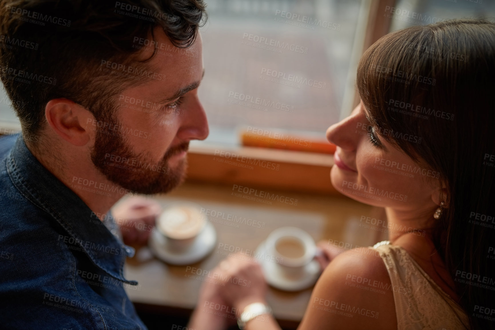 Buy stock photo Shot of an affectionate young couple looking lovingly into one another's eyes while sitting in a coffee shop during a date