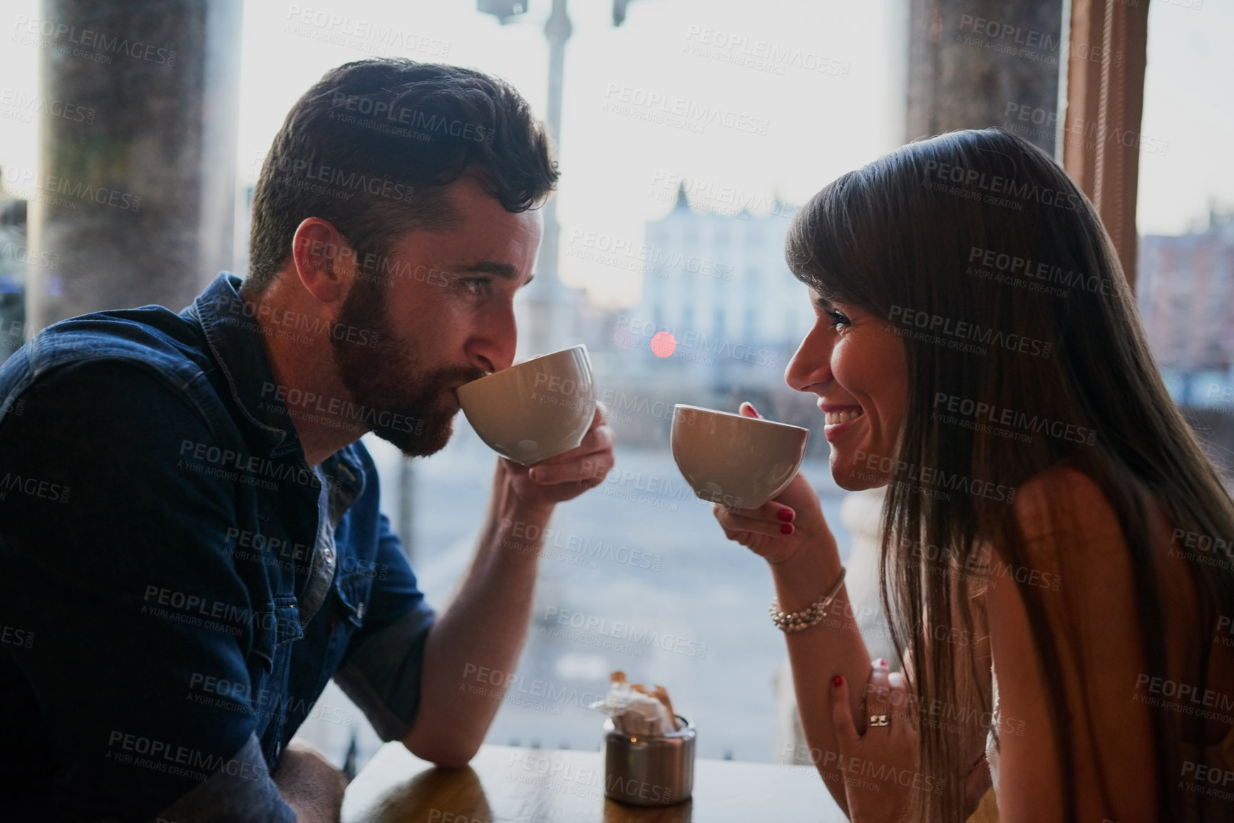 Buy stock photo Cropped shot of an affectionate young couple sitting in a coffee shop while on a date