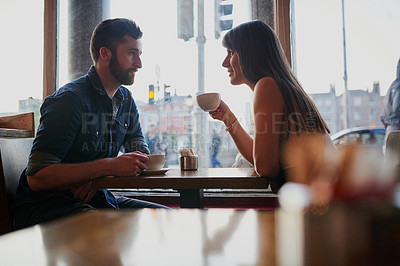 Buy stock photo Cropped shot of an affectionate young couple sitting in a coffee shop while on a date