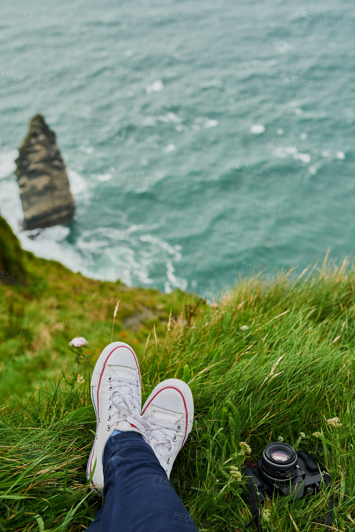 Buy stock photo High angle shot of an unrecognizable woman sitting on cliff and admiring the view