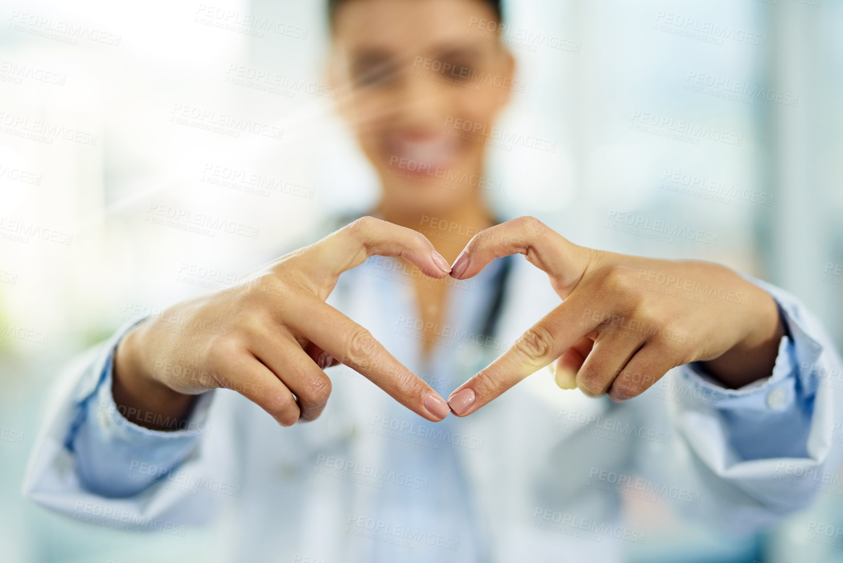 Buy stock photo Portrait of a young female doctor making a heart shape with her fingers