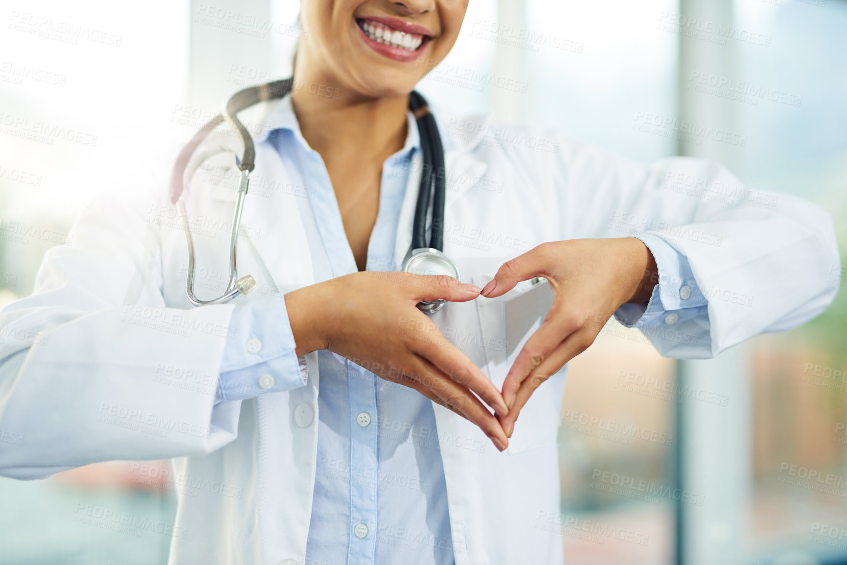 Buy stock photo Portrait of a young female doctor making a heart shape with her hands