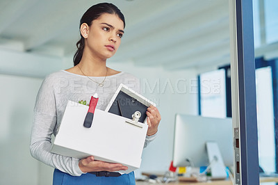 Buy stock photo Shot of an unhappy businesswoman holding her box of belongings after getting fired from her job