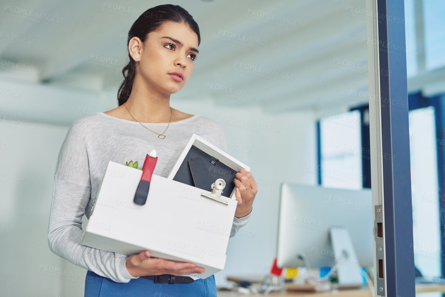 Buy stock photo Shot of an unhappy businesswoman holding her box of belongings after getting fired from her job