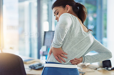 Buy stock photo Shot of a young businesswoman suffering from back pain while working in an office