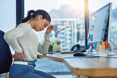 Buy stock photo Shot of a young businesswoman suffering from back pain while working in an office
