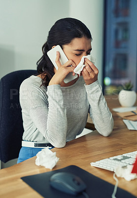 Buy stock photo Shot of a young businesswoman blowing her nose while speaking on a cellphone in an office