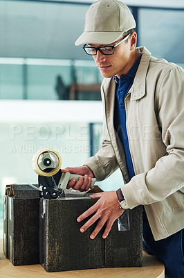 Buy stock photo Shot of a delivery man sealing a box with tape